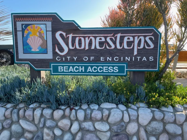 Stonestep Encinitas wooden sign in a garden of succlents